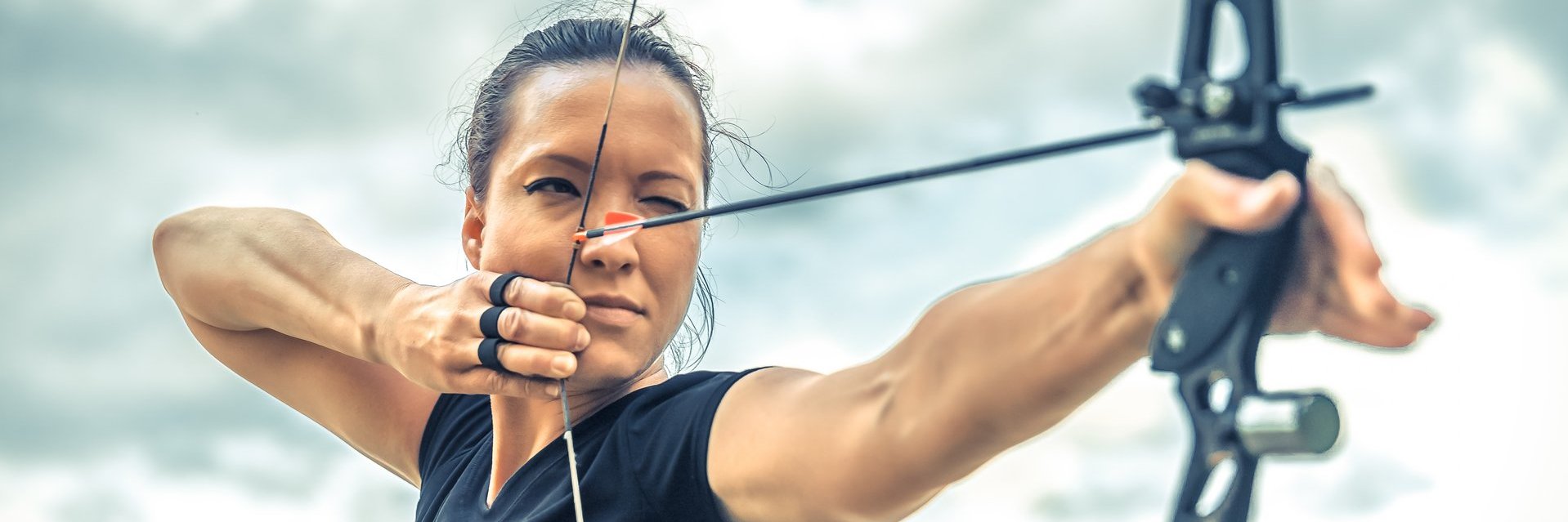 attractive-woman-archery-focuses-eye-target-arrow-from-bow